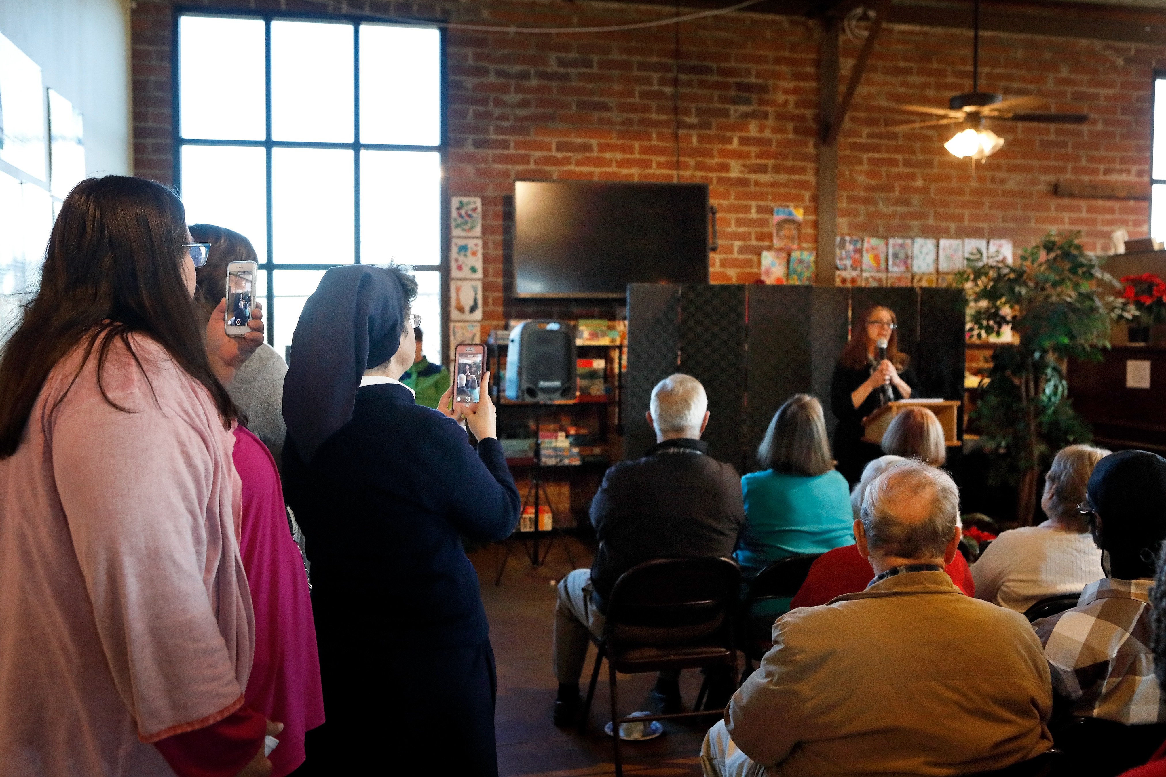 Community member Lisa Cannon speaks about how Daybreak provided her with spiritual care and physical support, as Daybreak director Sister Theresa Sullivan (second from left) records the moment.