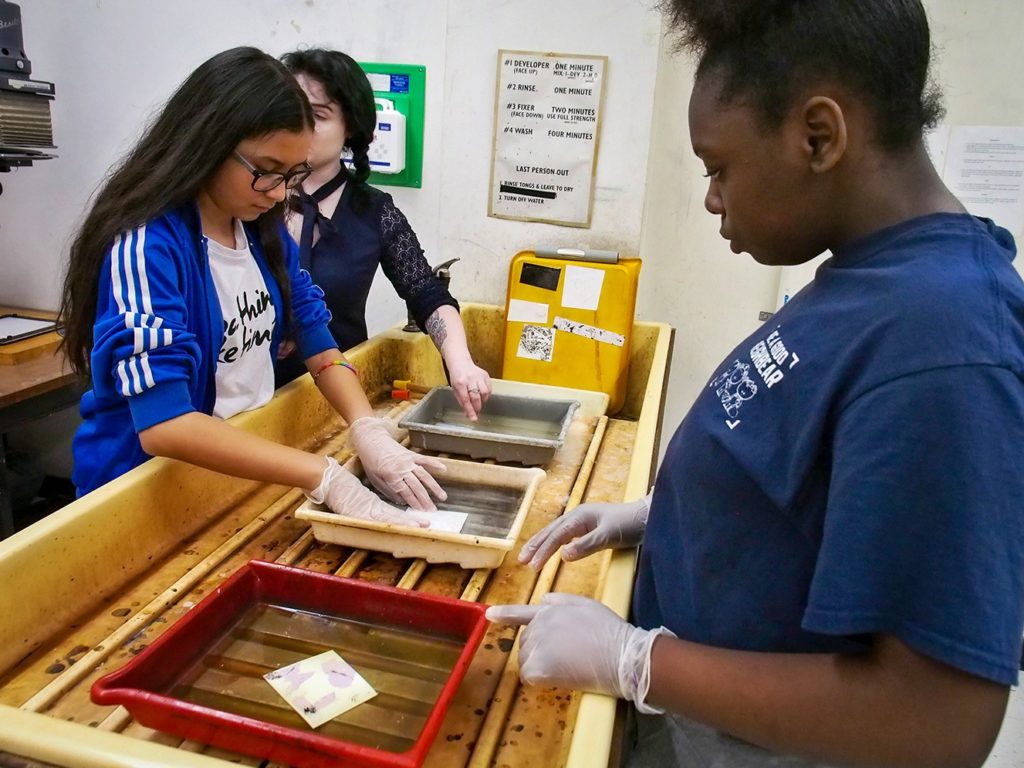 A Mercer student (right) helps Ballard Hudson middle students create a piece of art during their campus visit in April. 